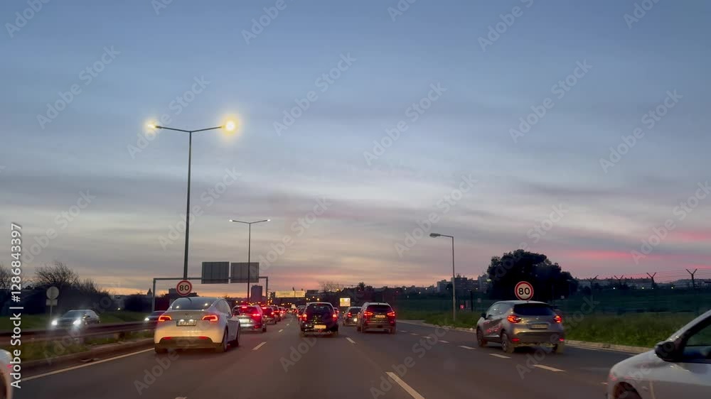 Carros em movimento na autoestrada ao entardecer com céu alaranjado

