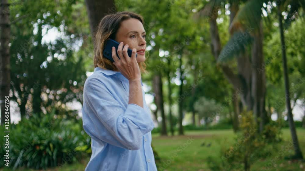 Relaxed woman strolling park calling mobile phone closeup. Smiling lady talking Relaxed woman strolling park calling mobile phone closeup. Smiling lady talking