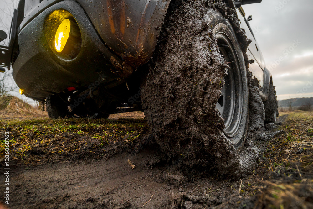 Close-up view of wheels with all-terrain tires. Off-road vehicle with 4-wheel drive. Mud stuck to the tread. Slippery ground after rain. Nature and travel