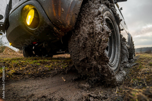 Obraz na płótnie Close-up view of wheels with all-terrain tires. Off-road vehicle with 4-wheel drive. Mud stuck to the tread. Slippery ground after rain. Nature and travel w salonie