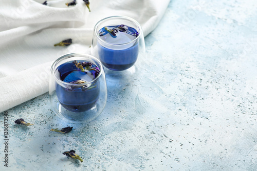 Cups of butterfly pea flower tea on blue grunge background with space for text photo