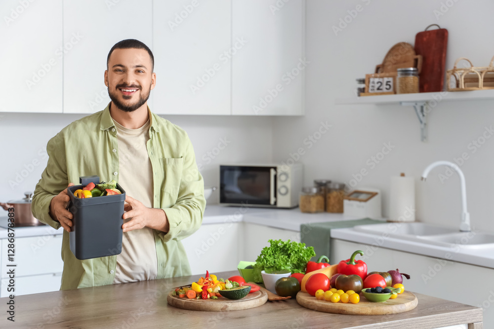 Young man with compost bin and vegetable scraps during cooking in kitchen Young man with compost bin and vegetable scraps during cooking in kitchen