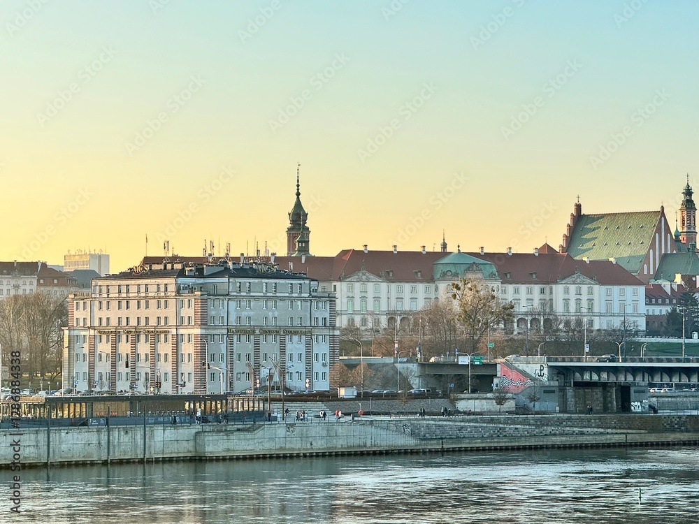 Obraz premium view of a bank of the vistula in the city of warsaw with a bridge and buildings at sunset