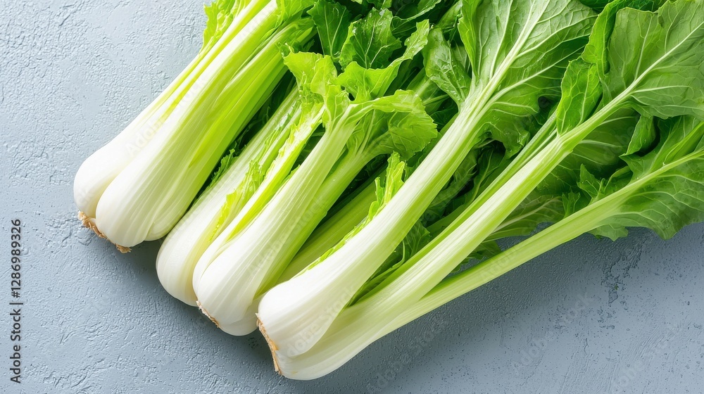 Fresh celery stalks with vibrant green leaves, arranged elegantly on a light background, showcasing their crisp texture and nutritional appeal. Fresh celery stalks with vibrant green leaves, arranged elegantly on a light background, showcasing their crisp texture and nutritional appeal.