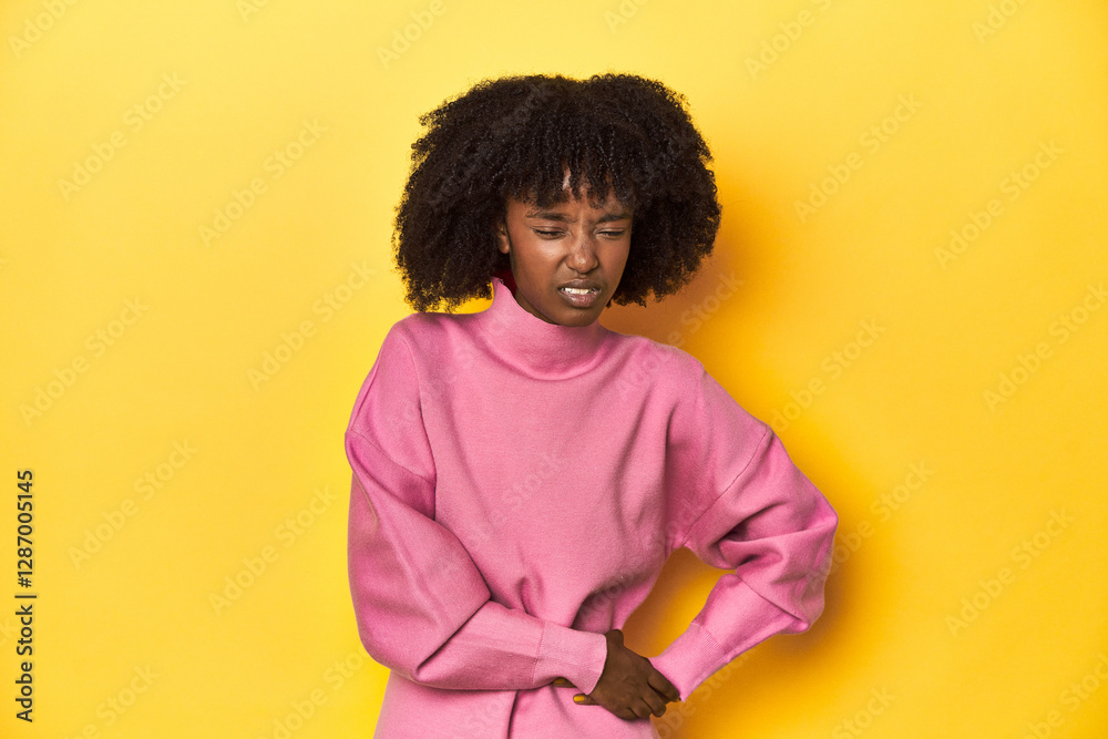 Teen girl in pink sweatshirt, yellow studio backdrop having a liver pain, stomach ache. Teen girl in pink sweatshirt, yellow studio backdrop having a liver pain, stomach ache.