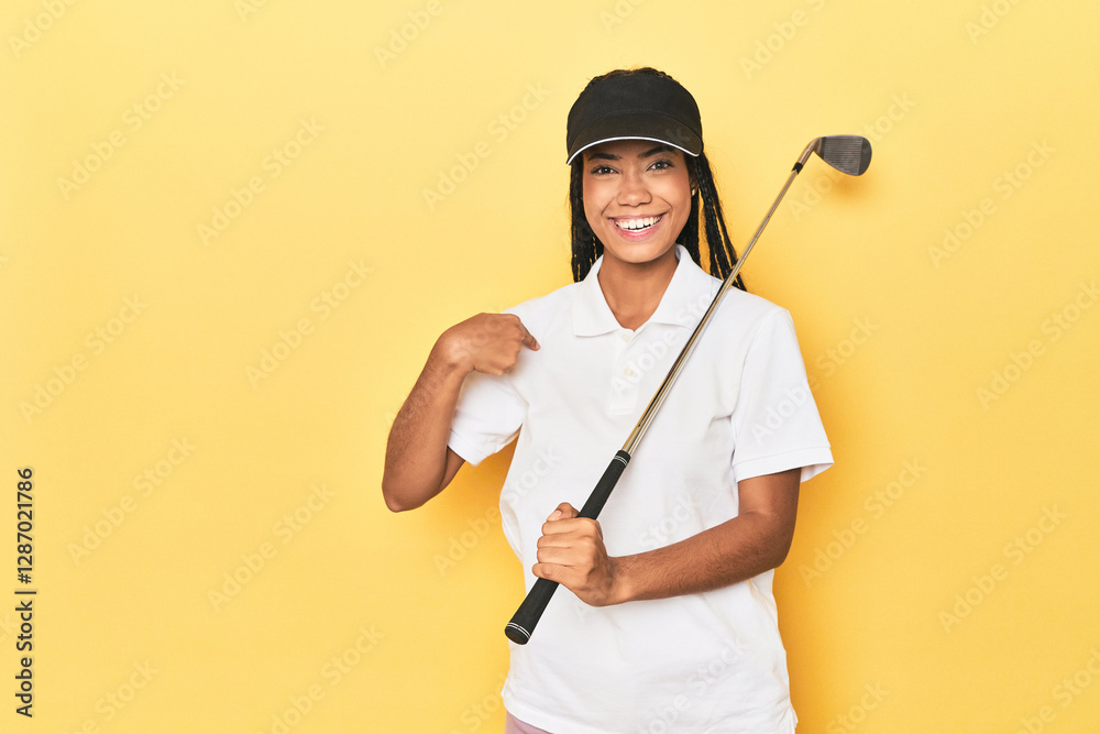 Indonesian female golfer on yellow backdrop person pointing by hand to a shirt copy space, proud and confident