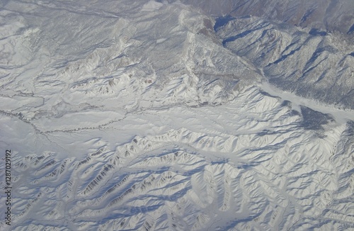 a gray mountain landscape that slopes and peaks with ridges, dips, and crevasses forming into a canyon perhaps from another planet