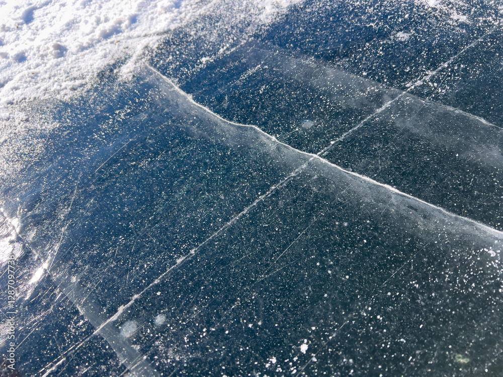 A close-up of a frozen surface with visible cracks and snowflakes, capturing the intricate details and natural patterns formed in the ice.