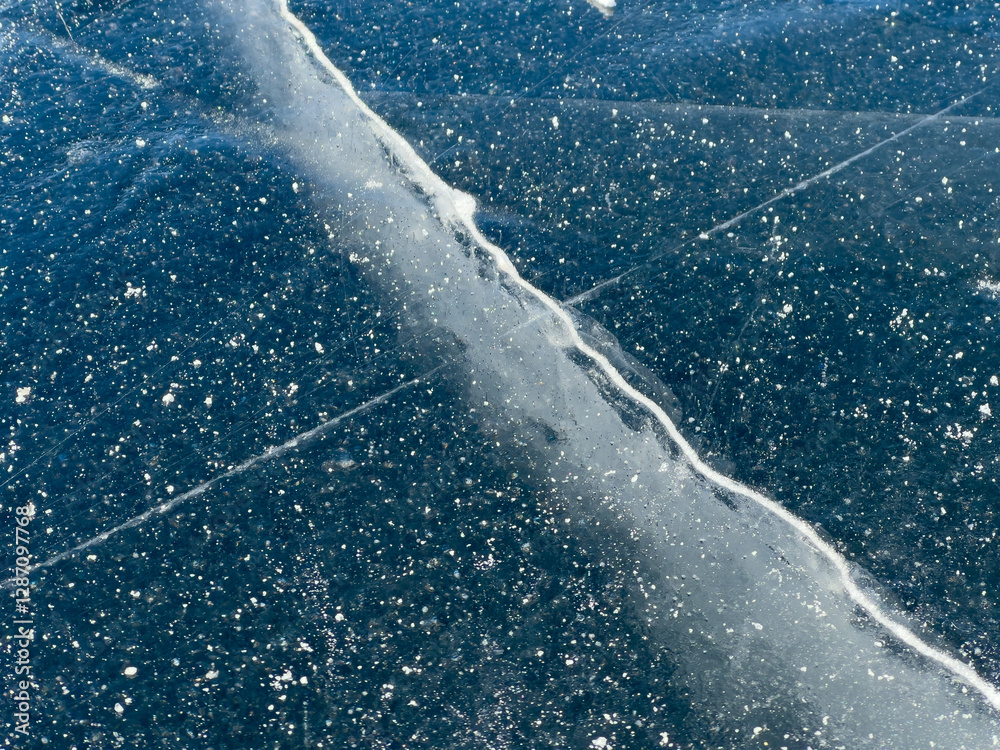A close-up view of a frozen surface with visible cracks and air bubbles, capturing the intricate details and natural patterns of the ice.