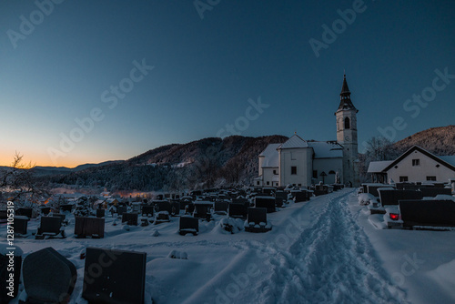 Obraz na płótnie Beautiful church at Ljubno ob Savinji in cold winter morning. Visible haze from the river, sun rising up and smoke coming out of smokestacks. w salonie