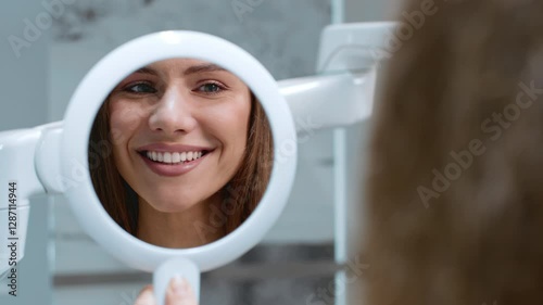 Woman patient smiles at her reflection, highlighting a positive dental experience during a routine check-up.