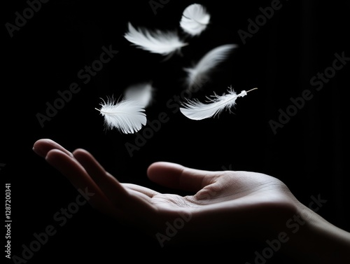 Feathers falling from hand in darkness	