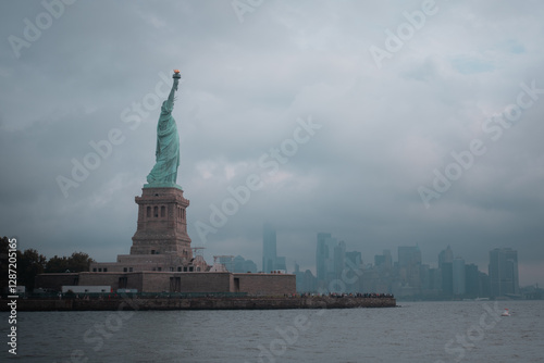 Distant view of the Statue of Liberty on Liberty Island, New York City, with a cloudy sky.