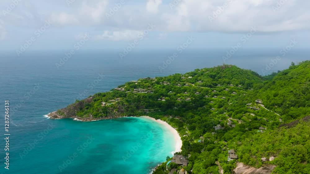 Green hills slope towards a turquoise bay surrounded by villas and dense tropical forests. Seychelles, Mahe. Green hills slope towards a turquoise bay surrounded by villas and dense tropical forests. Seychelles, Mahe.