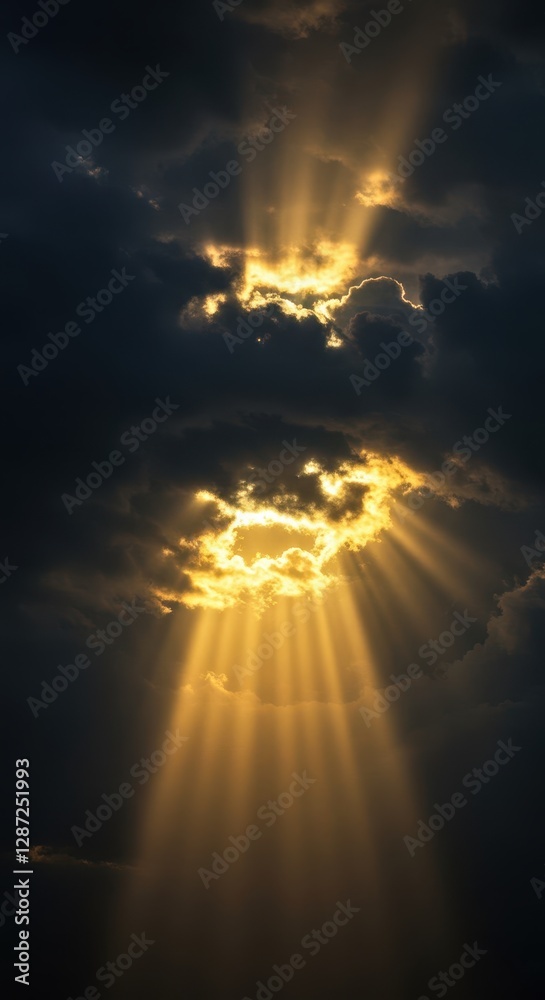 Obraz premium Majestic sunbeams breaking through dramatic clouds at sunset