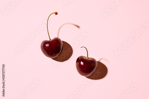 pair of cherries on a pink background