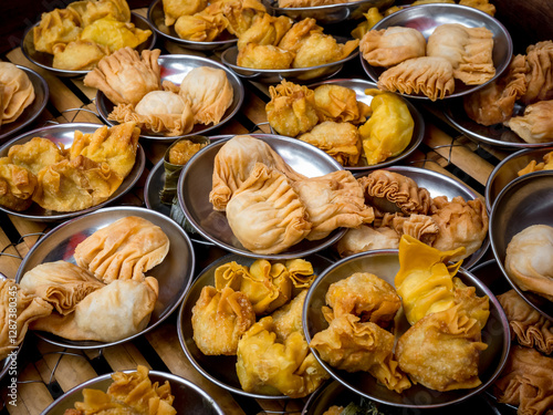 Many oriental crispy deep fried wontons in small stainless steel mini bowl preparing in local restaurant, Chinese dim sum takeaway finger food. Fried halal chicken wontons, tasty breakfast background.