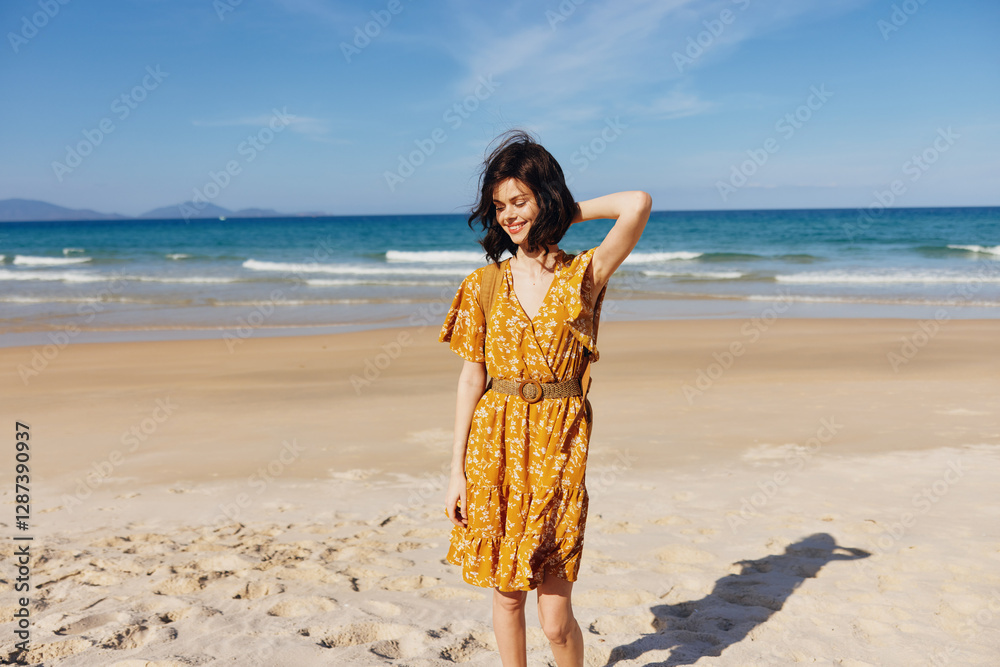 Beautiful woman in a yellow dress standing on a sandy beach with the ocean in the background, enjoying the serene view Beautiful woman in a yellow dress standing on a sandy beach with the ocean in the background, enjoying the serene view