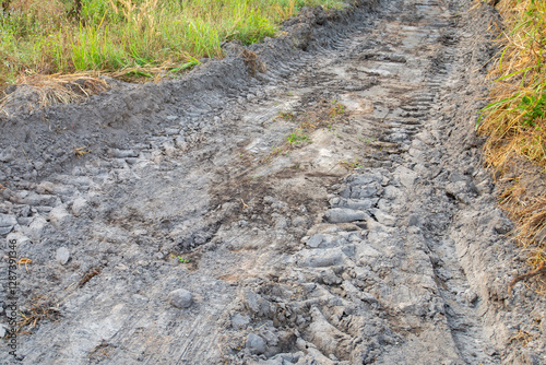 Dirt road with large tire marks running through it.