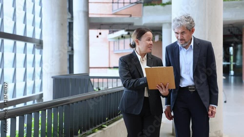 Asian senior executive manager is looking at new marketing strategy investment plan from his secretary for international business expansion and globally success concept