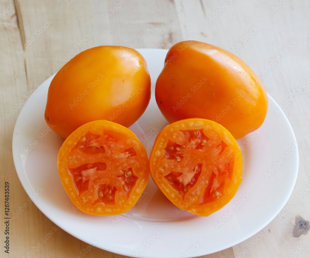 Whole and sliced Orange Queen  tomatoes on a white plate