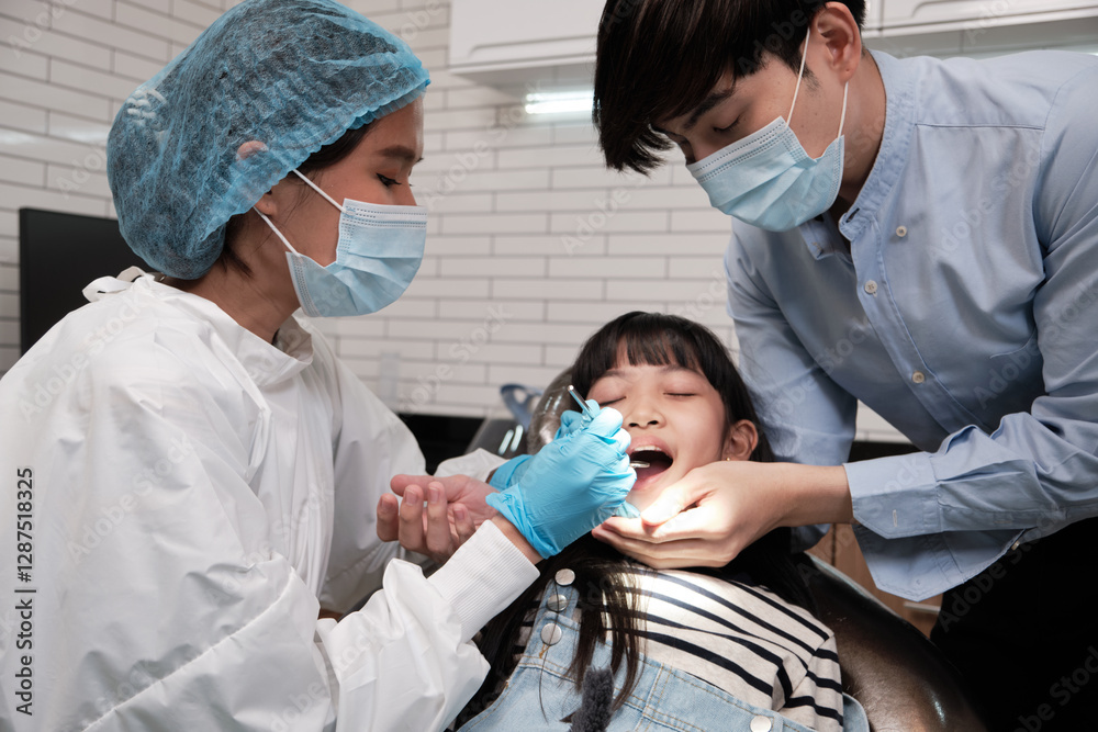 Obraz premium Asian female pediatric dentist examines a girl's teeth in dental clinic and takes care and encourages of father, mouth oral hygiene, and professional orthodontic healthcare work in a kid hospital.
