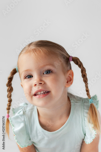 Portrait of little girl on white with plaited pigtails photo