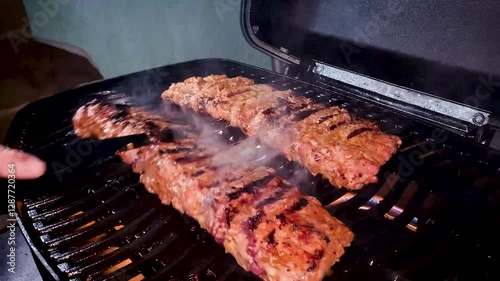 Ribs on a gas grill fire cooking and flipped toasted
