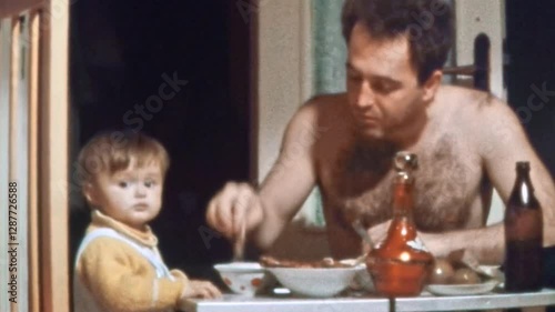 Comical father trying to feed child at home. Funny dad eating food at table, playing, joking with small kid. Happy family memories with children, parents. Archival vintage film. Retro 1980s archive