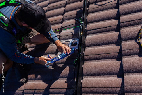 Tradesman electrician weather sealing cables on roof on solar panel system installation