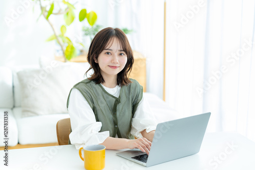 自宅でノートパソコンを操作する若い女性