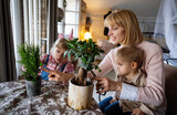 Happy single parent, woman with a little son is planting houseplants at home. Home gardening