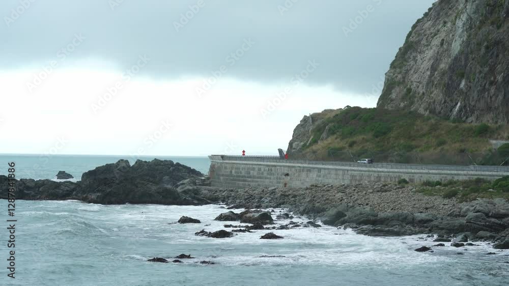 A coastal road meanders along a rocky shoreline, set against a beautifully cloudy sky A coastal road meanders along a rocky shoreline, set against a beautifully cloudy sky