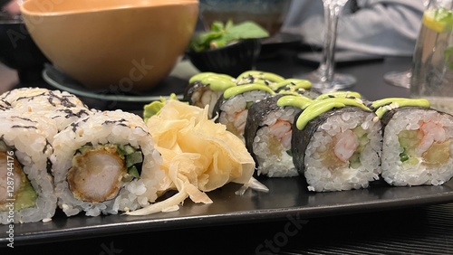 Close-up shot of a platter featuring two types of sushi rolls. The platter rests on a dark rectangular plate. Japanese cuisine, seafood, and healthy eating concept.
