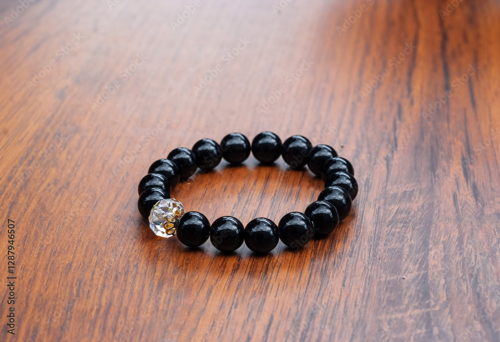 Black Bracelet with Natural Onyx Stones and White Crystal on a Wooden Table