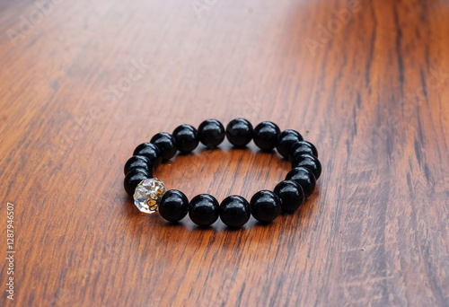 Obraz na płótnie Black Bracelet with Natural Onyx Stones and White Crystal on a Wooden Table w salonie