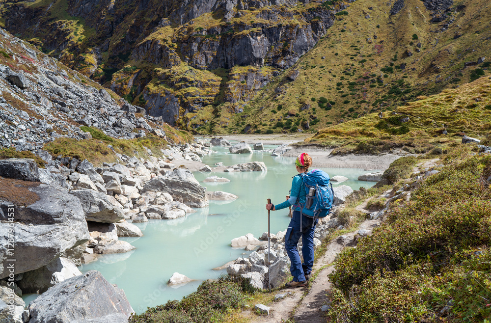 Female trekker dressed active style with backpack enjoying glacier river on Mera peak climbing route near high altitude Sabai Tso glacial lake cca 4350m. Makalu Barun National Park, , Nepal. Female trekker dressed active style with backpack enjoying glacier river on Mera peak climbing route near high altitude Sabai Tso glacial lake cca 4350m. Makalu Barun National Park, , Nepal.