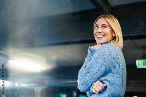 Portrait of a smiling woman in a blue sweater indoors with a dark background photo