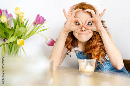 Portrait of woman making face while sitting with drink at table in room