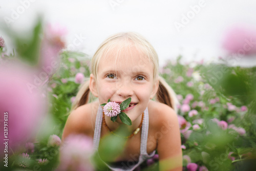 Portrait of smiling girl with clover flower in her mouth photo