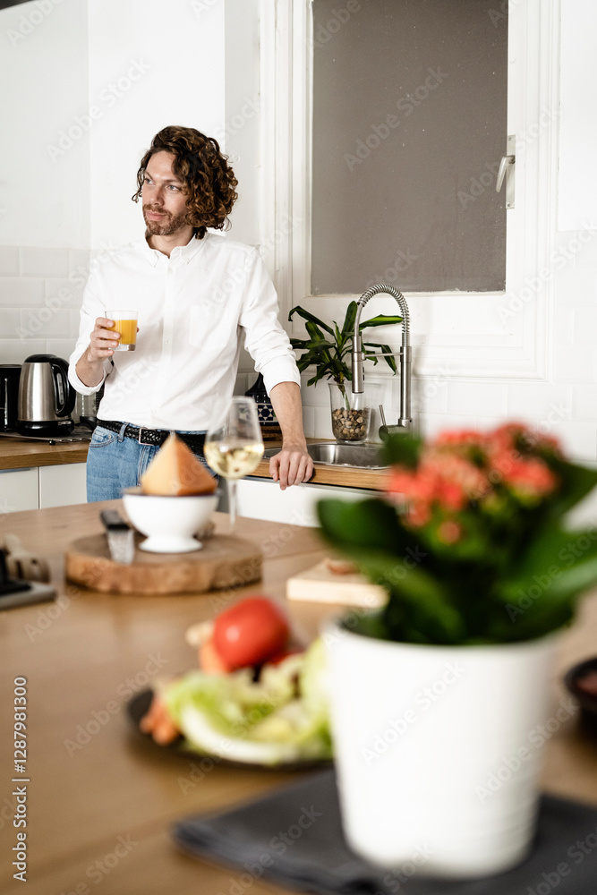 Man holding glass of orange juice in kitchen at home Man holding glass of orange juice in kitchen at home