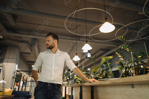Mature businessman standing at a counter in modern office lounge