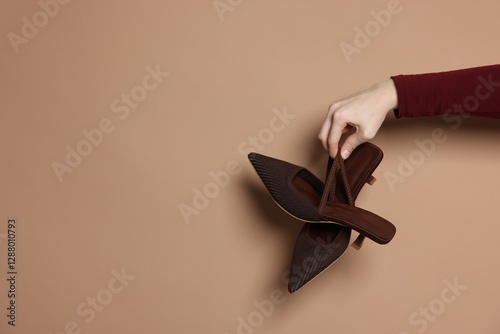 Woman showing stylish high-heeled shoes on beige background, closeup. Space for text photo