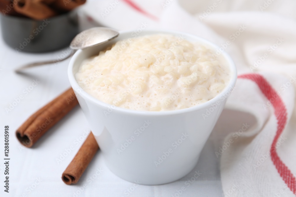 Tasty rice pudding with cinnamon served on white tiled table, closeup Tasty rice pudding with cinnamon served on white tiled table, closeup