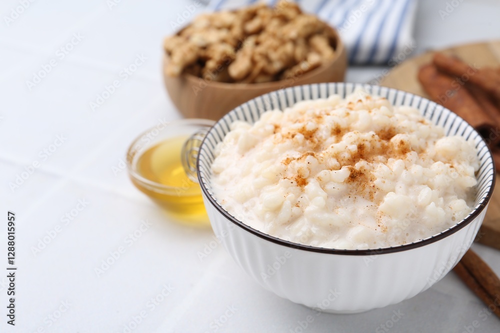 Tasty rice pudding with cinnamon served on white tiled table, closeup Tasty rice pudding with cinnamon served on white tiled table, closeup