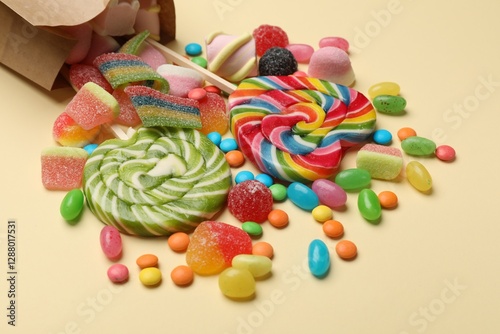 Different delicious candies and marshmallows on beige background, closeup