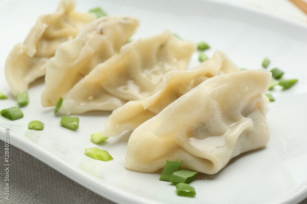 Tasty boiled gyoza (dumplings) with green onion on white table, closeup Tasty boiled gyoza (dumplings) with green onion on white table, closeup
