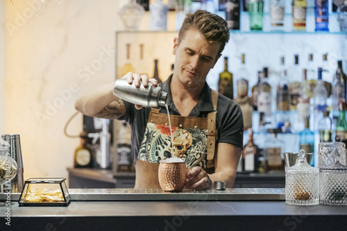 Bartender mixing cocktail in a bar, using cocktail mixer photo