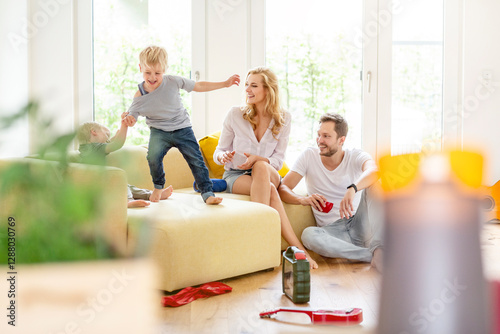 Happy family in living room of their new home with boys romping about photo