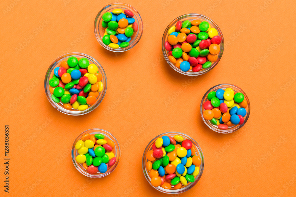 different colored round candy in bowl and jars. Top view of large variety sweets and candies with copy space different colored round candy in bowl and jars. Top view of large variety sweets and candies with copy space